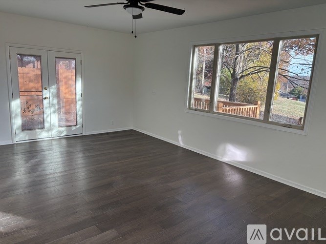 A room with a ceiling fan and a large window showing an outdoor view.