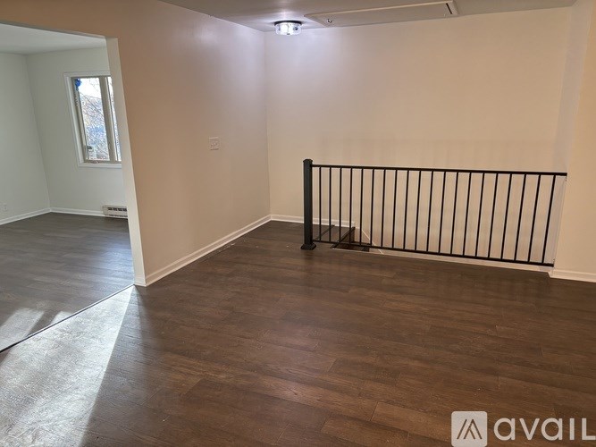 A room with a black railing and wooden flooring.