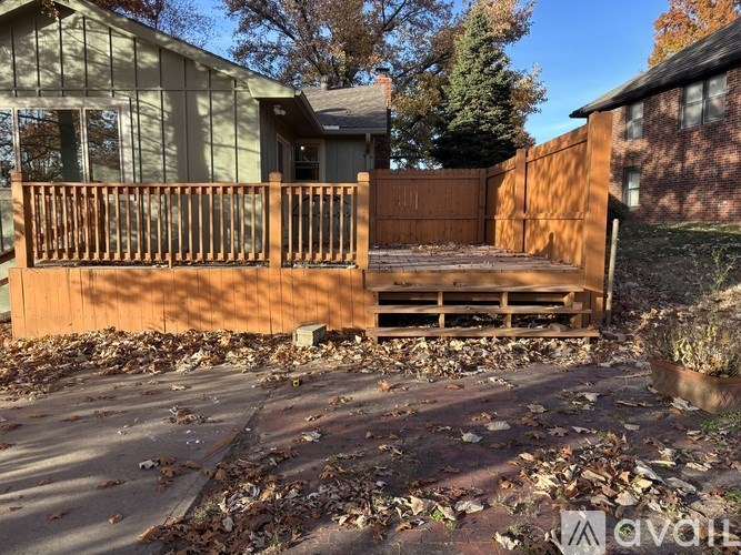 A wooden deck with a bench and a fence in front of a house.