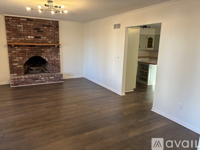 A room with a brick fireplace and wooden flooring.