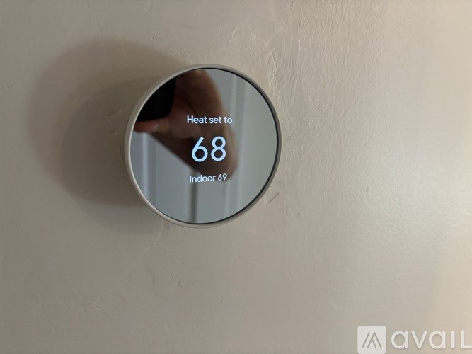 A round mirror on a wall showing a hand with the text "Heat set to Indoor 68" and "Available".