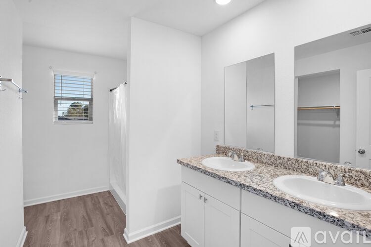 A bathroom with a large mirror, sink, and a window with blinds.
