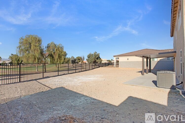 A large, empty yard with a fence and a house in the background.