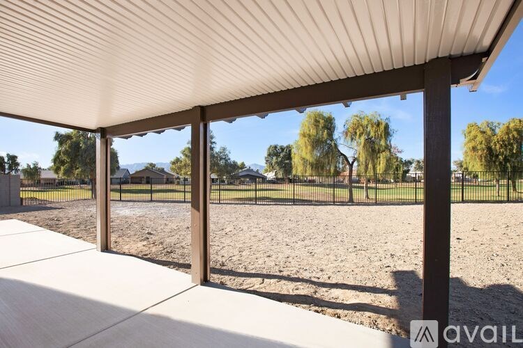 A patio with a white roof and a view of a fenced field.