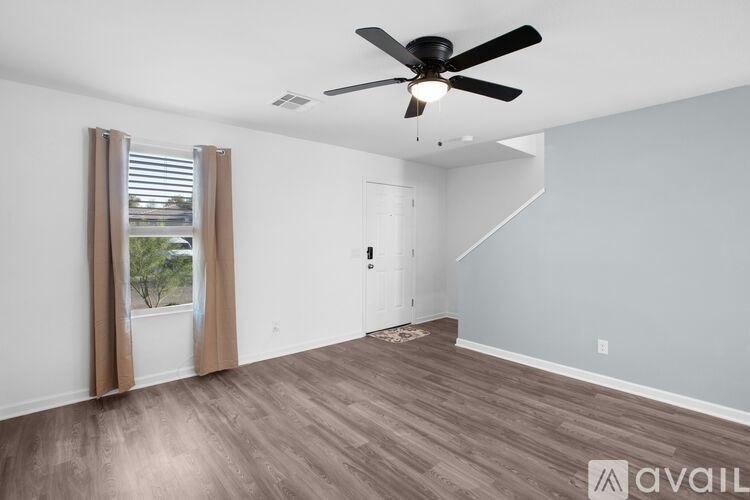 A room with a ceiling fan and wooden flooring.