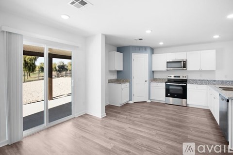 A modern kitchen with white cabinets and a wooden floor.
