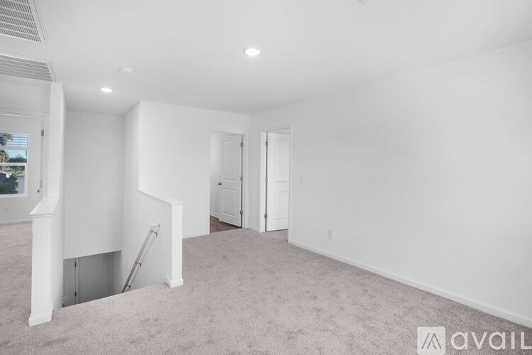 A spacious, empty room with a carpeted floor and white walls.