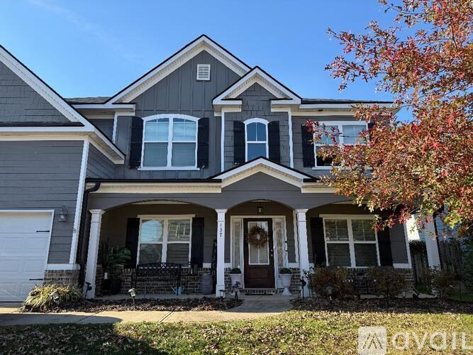 A two-story house with a grey and black exterior and a white door.
