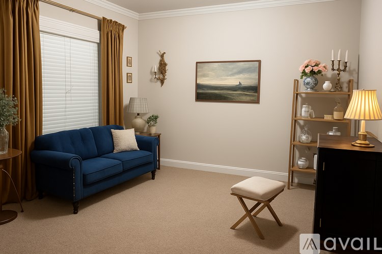 A living room with a blue sofa, a painting on the wall, and a carpet on the floor.