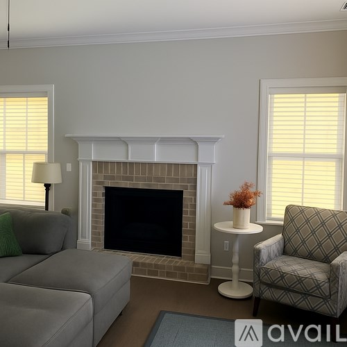 A living room with a grey couch, a white end table, and a fireplace.