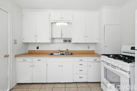 A kitchen with white cabinets and a wooden counter top.