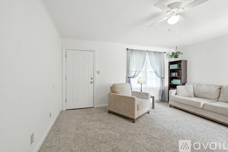 A living room with a couch, chair, and a fan.