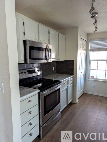 A kitchen with white cabinets and black appliances.