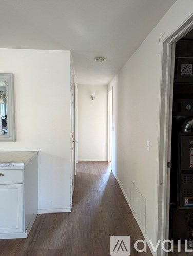 A long hallway with a white door on the left and a black door on the right.