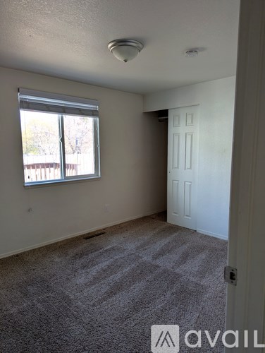 A room with a carpeted floor and a window with blinds.