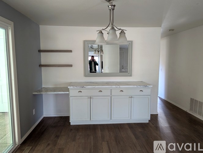 A large white cabinet with a mirror above it in a room with wooden floors.