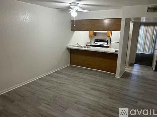 A room with a kitchenette and a ceiling fan.