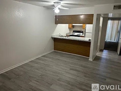 A room with a kitchenette and a ceiling fan.