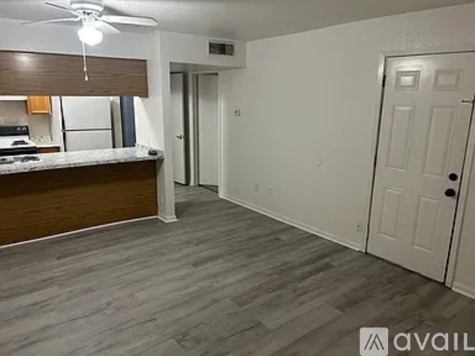 A room with a fan and a counter with a window.