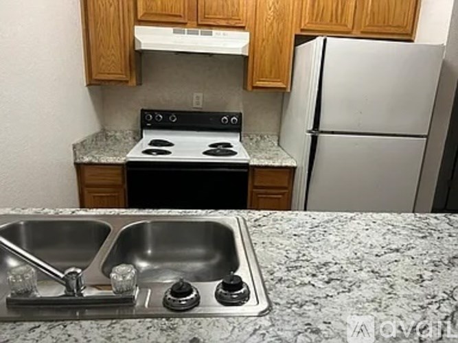 A kitchen with a stove, sink, and refrigerator.