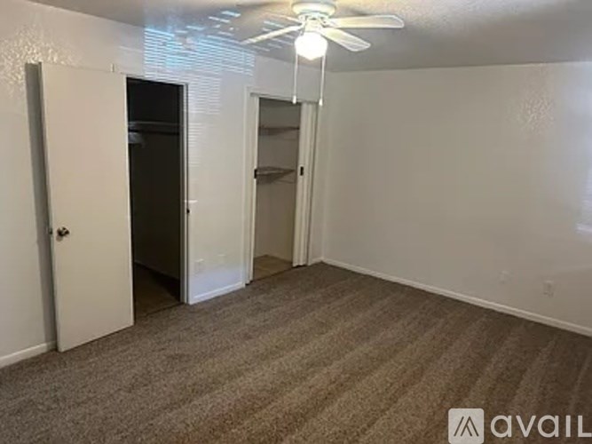 A room with a carpeted floor and a ceiling fan.