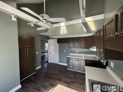 A kitchen with a fan and wooden floors.