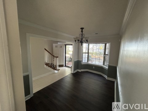 A spacious room with a staircase and a chandelier.