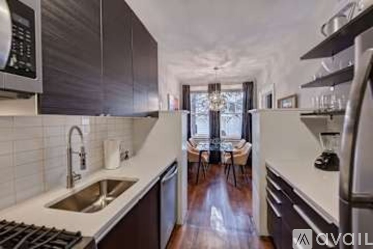 A modern kitchen with dark brown cabinets and white countertops.