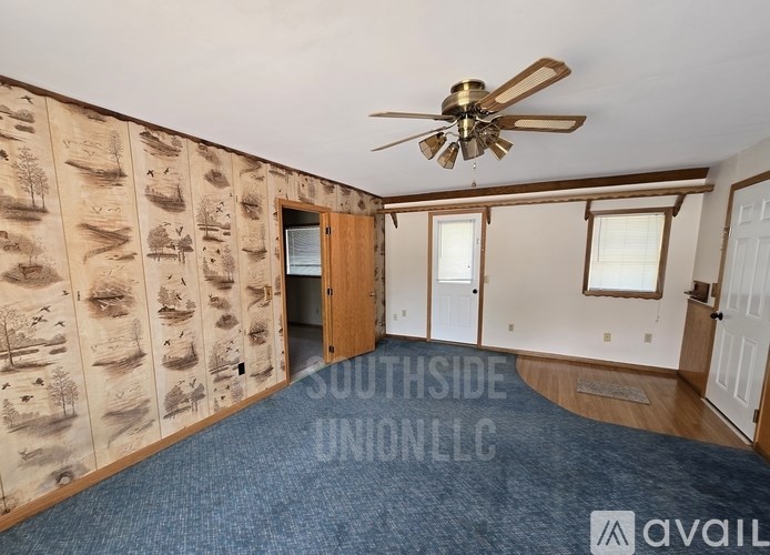 A room with a ceiling fan and a wall covered in drawings of trees.