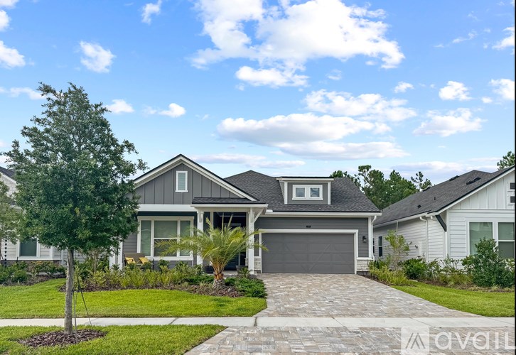 A house with a driveway and a tree in front of it.