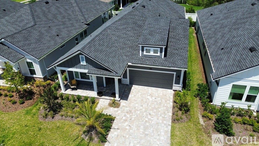 A house with a grey roof and a stone pathway leading to the garage.