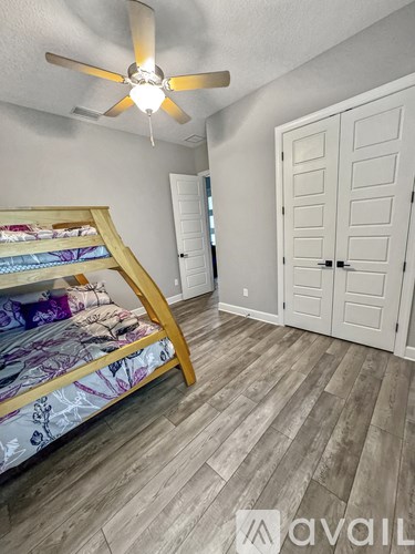 A bedroom with a bed, a ceiling fan, and a wardrobe.