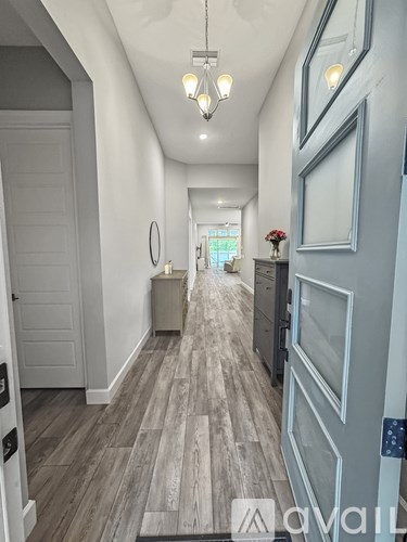 A hallway with a wooden floor and white walls.