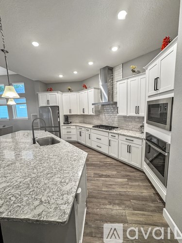 A kitchen with white cabinets and a marble countertop.