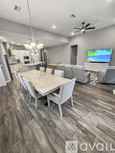 A modern dining room with a wooden floor and a television on the wall.