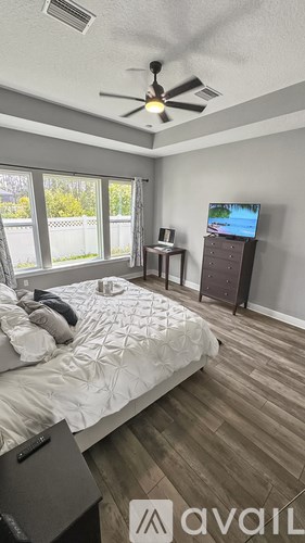 A bedroom with a bed, a ceiling fan, and a television.