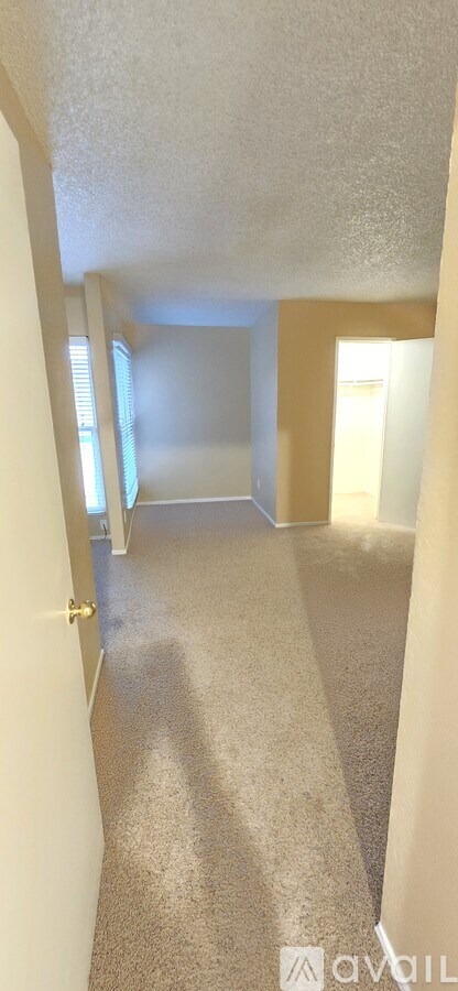 A hallway with a carpeted floor and white walls.
