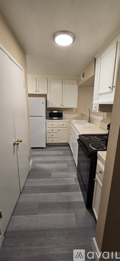 A kitchen with white cabinets and a black stove top oven.