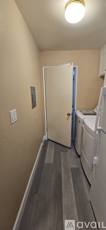 A small room with a door and a refrigerator.