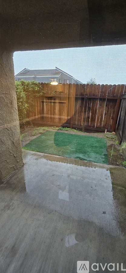 A backyard with a wooden fence and a green patch of grass.