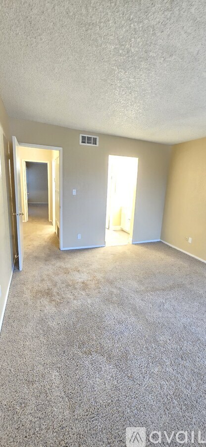 A room with a carpeted floor and a doorway leading to another room.