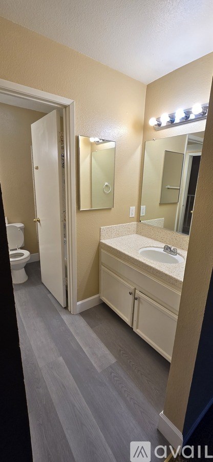 A bathroom with a toilet, sink, and mirror.