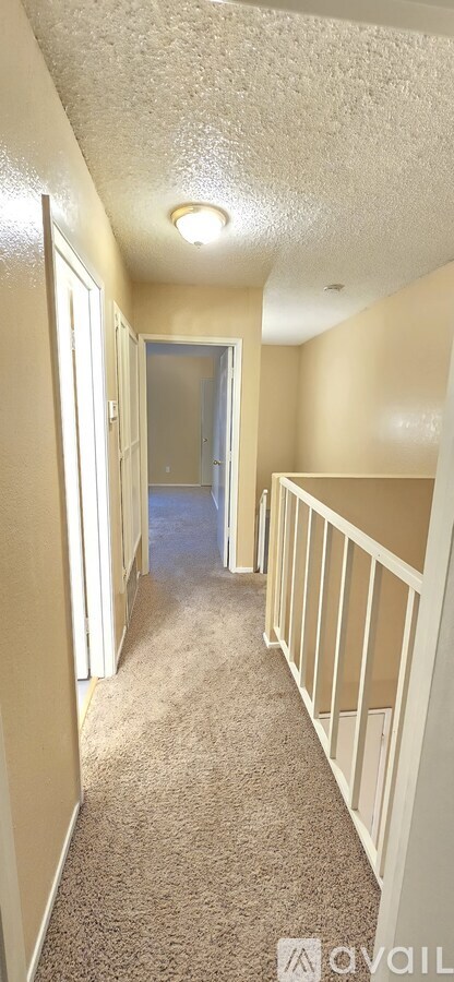 A hallway with carpeted floors and white walls.