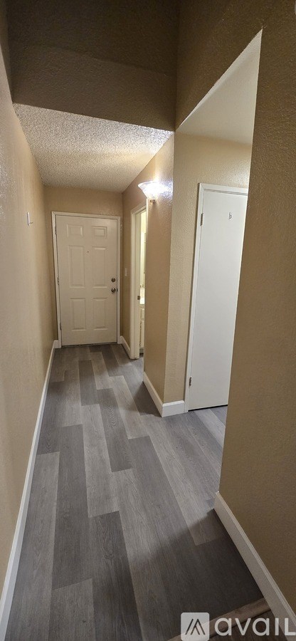 A hallway with a carpeted floor and white doors.
