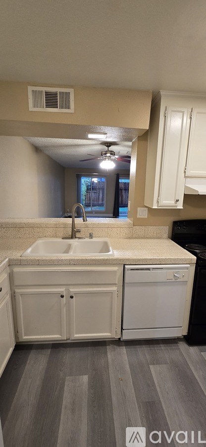 A kitchen with white cabinets and a black dishwasher.