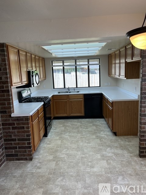 A kitchen with wooden cabinets and a brick wall.