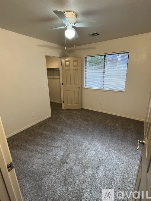 A room with a ceiling fan and carpeted floor.