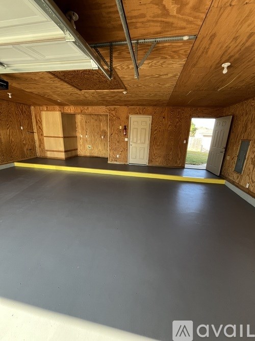 A large empty room with wooden walls and a grey floor.