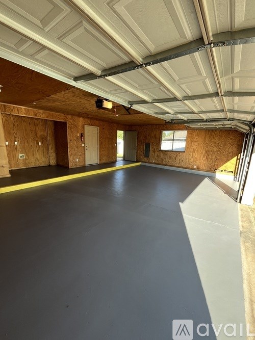 A spacious garage with a grey floor and wooden walls.