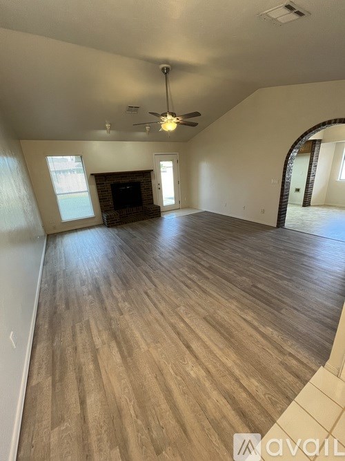 A spacious room with wooden flooring and a fireplace.